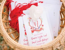 red and white ceremony programs with watercolor monogram crest