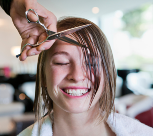 Hairdresser cutting bangs on woman