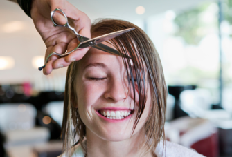 Hairdresser cutting bangs on woman