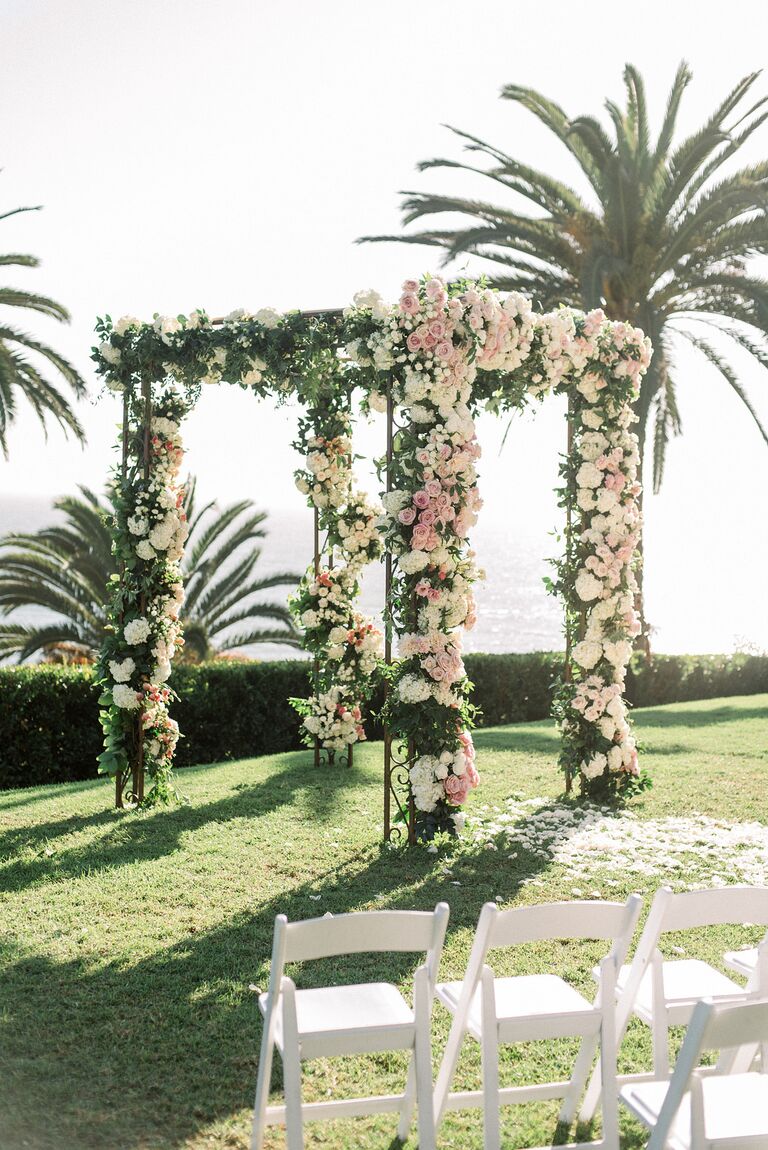 Chuppah covered in pink roses at oceanfront wedding.