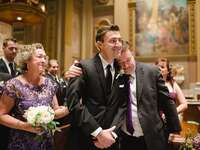 A tender moment shows the father of the groom hugging his son, as the young man smiles broadly on his wedding day.