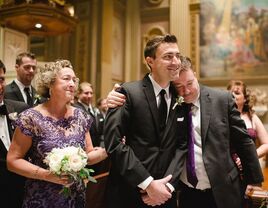 A tender moment shows the father of the groom hugging his son, as the young man smiles broadly on his wedding day.