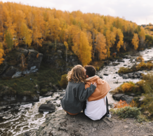 Couple sitting on rock together overlooking river