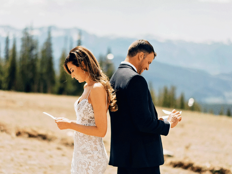 Bride and groom standing back to back reading love letters from each other.