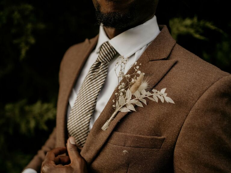 Groom wearing neutral brown suit with dried floral boutonniere