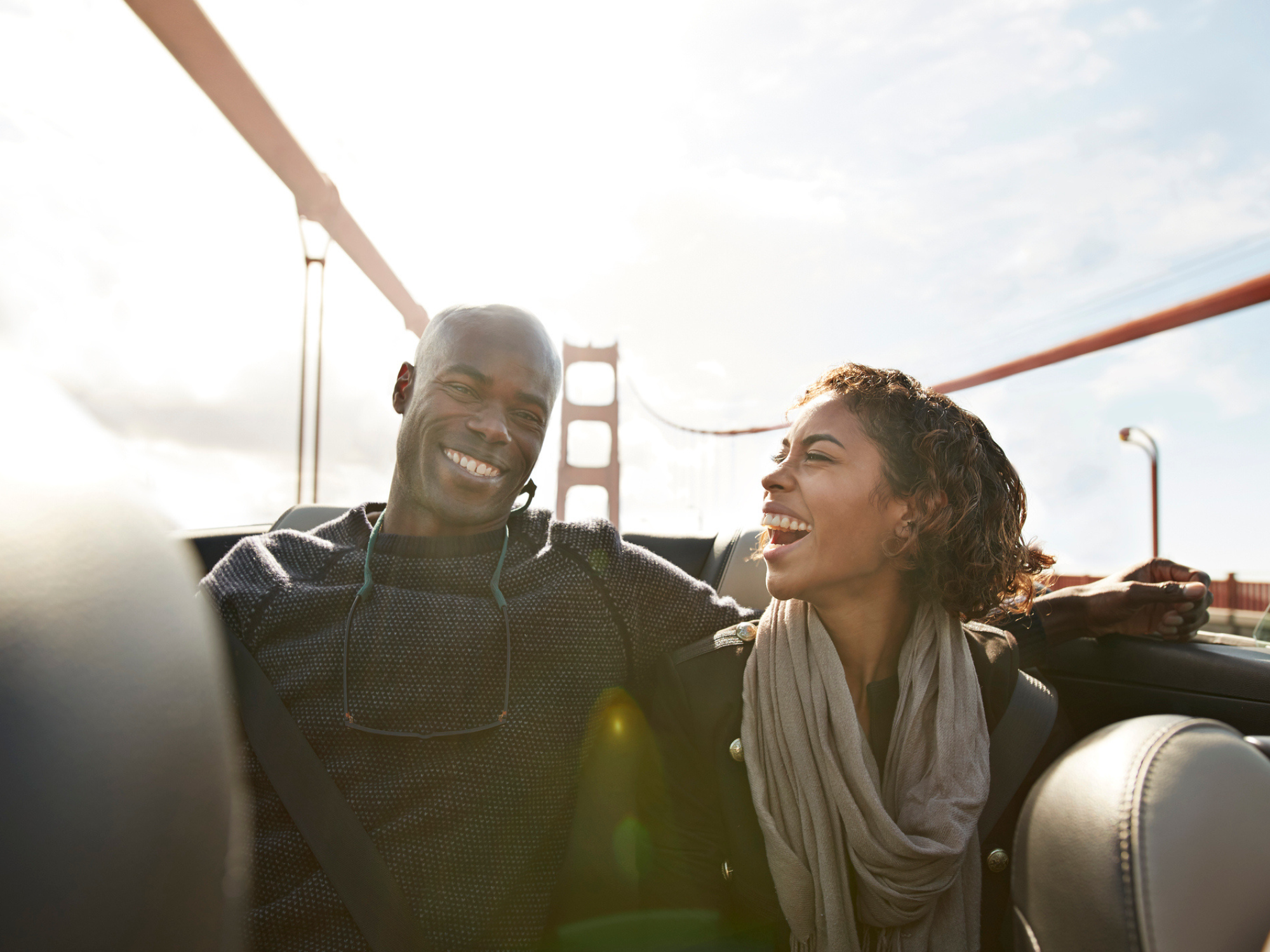 Couple smiling at each other while riding in car on Golden Gate Bridge in San Francisco, California