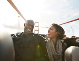 Couple smiling at each other while riding in car on Golden Gate Bridge in San Francisco, California