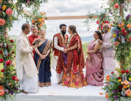 Bride and groom standing with families at altar during outdoor Indian wedding ceremony