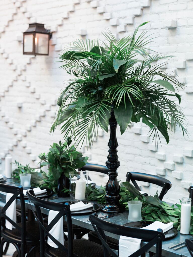 Lush tropical palm leaves as reception centerpieces in sleek black vases