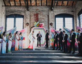 Bride and groom getting married at colorful wedding ceremony in rustic building