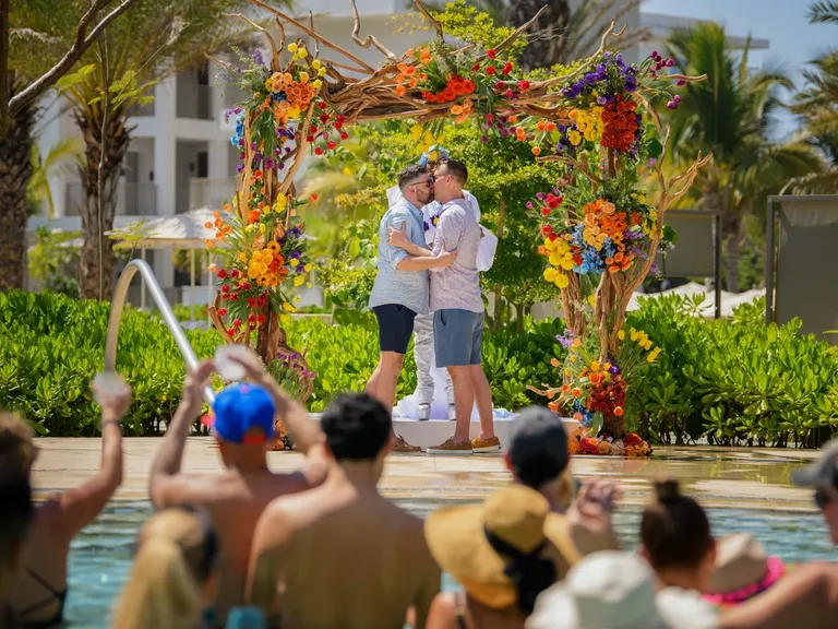gay couple kissing under floral altar outside