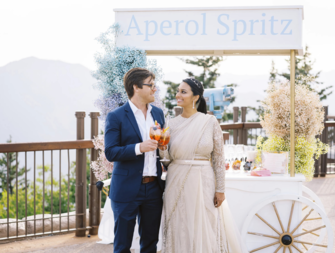Bride and groom beside aperol spritz wedding drink station