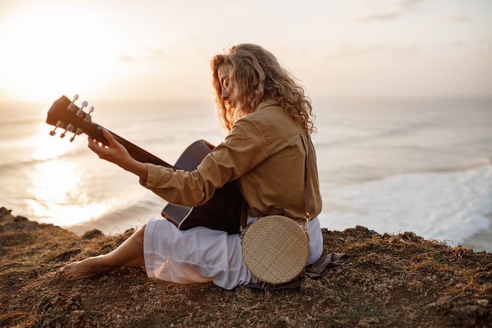 woman playing guitar near the ocean