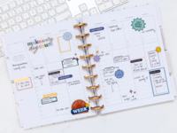 Planner open on computer desk with stickers and writing inside