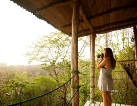 woman standing on a balcony with a camera overlooking beautiful costa rica rainforest and scenery