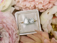 A lovely two-stone engagement ring surrounded by flowers.