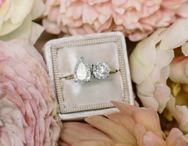 A lovely two-stone engagement ring surrounded by flowers.