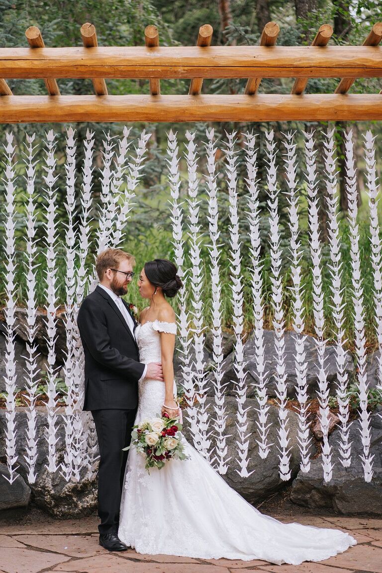 Couple posing in front of origami crane garlands