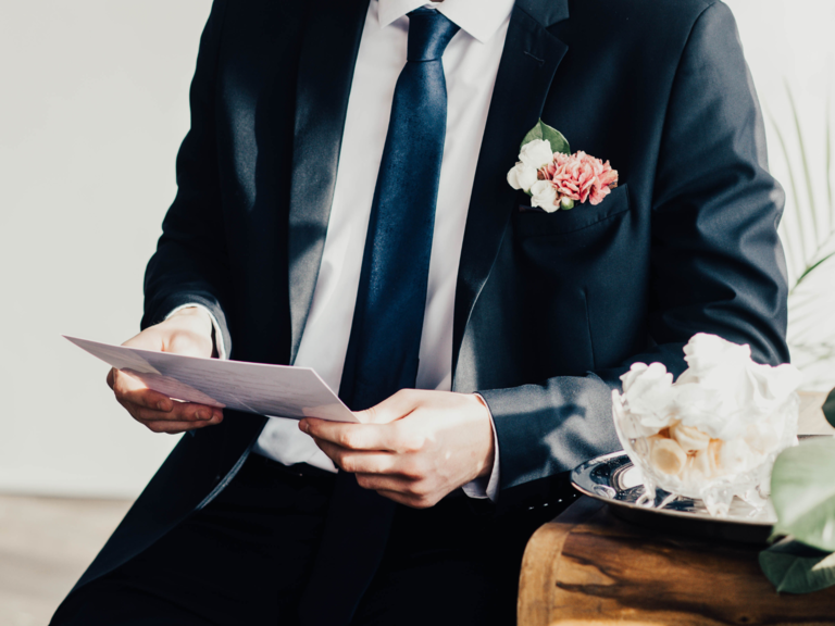 Groom reading letter from parents on wedding day