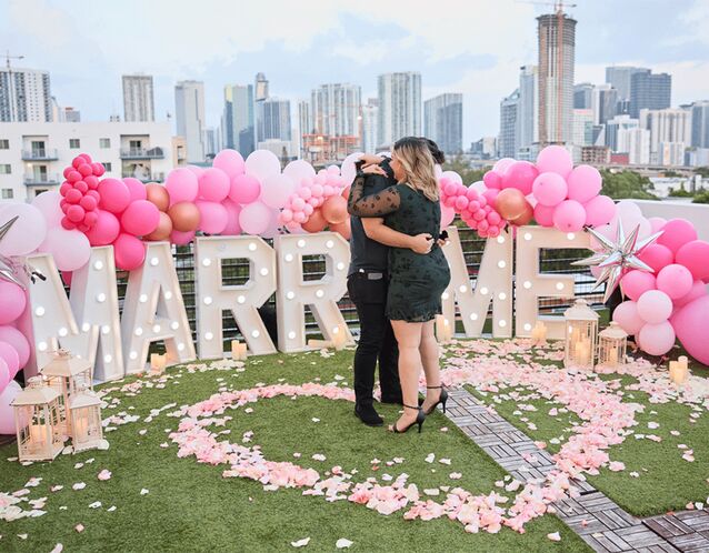 Couple hugging in front of "Marry me" sign