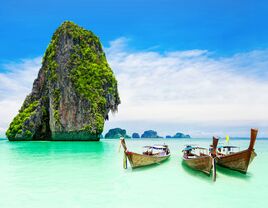 Scenic beach in Thailand with boats and stunning sea stack