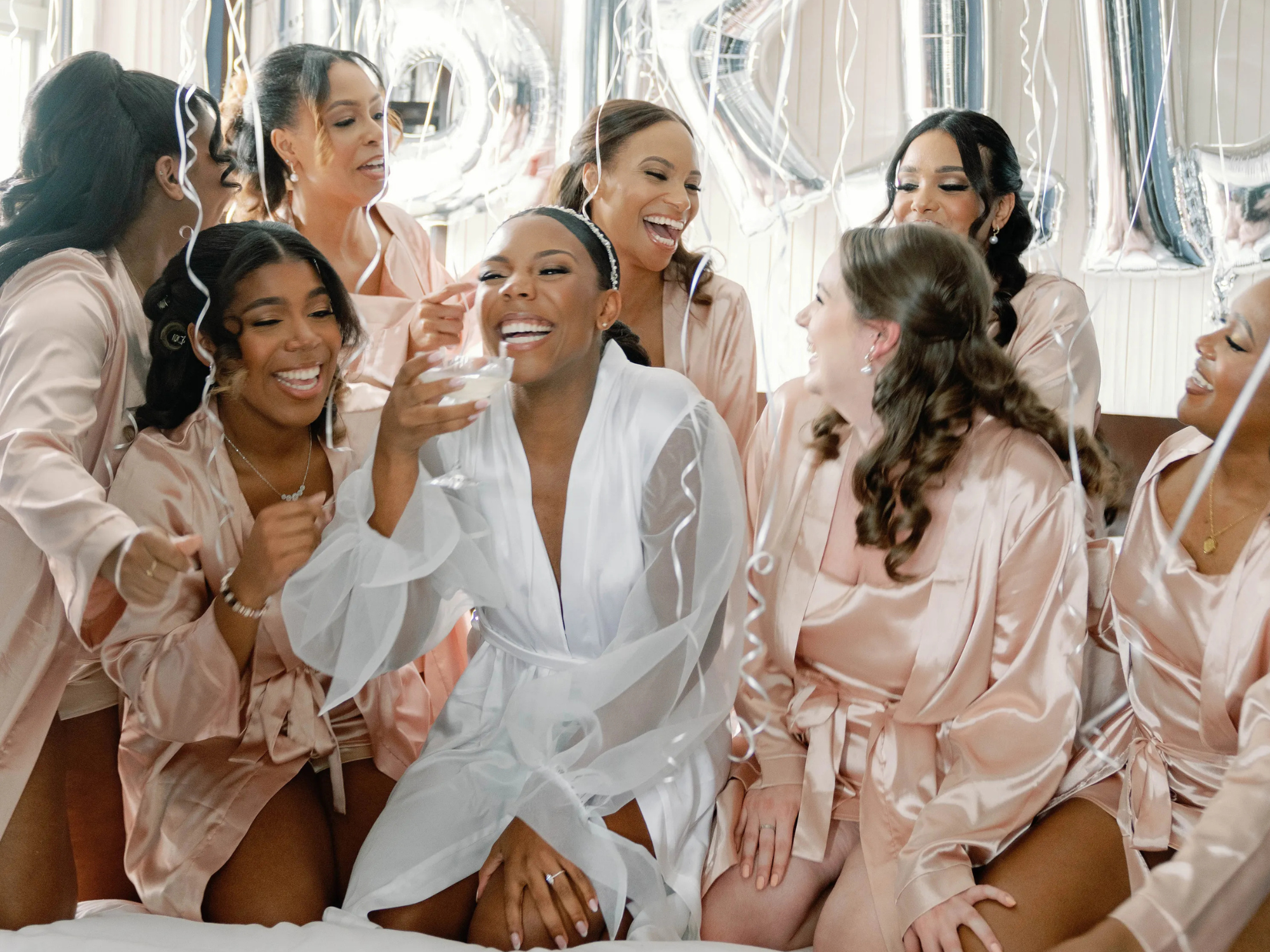 Bride with bridal party wearing light pink bridesmaid robes