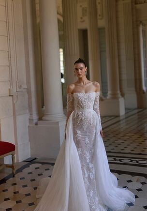 A blend of textured fabric and lace shapes Parade, a gown from WONÃ Concept's Maison Blanche line. The fitted contour cascades into a mermaid outline with exposed shoulders, a low open back, and exposed bodice boning. Floral details and shimmering beading trace the surface down to a high skirt slit. Detachable long sleeves and an airy detachable overskirt transition the piece into an A-line silhouette, concluding with a court length train.