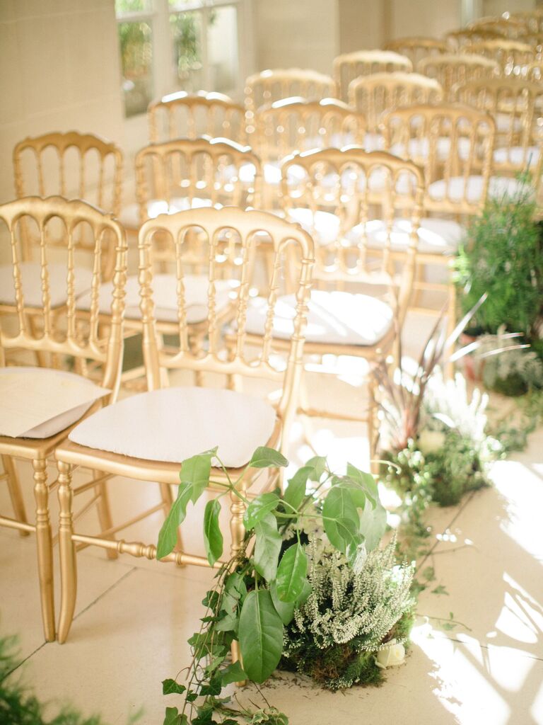 rows of gold opera chairs at wedding ceremony with greenery aisle markers