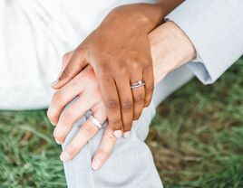 Couple holding hands showing off wedding and engagement rings