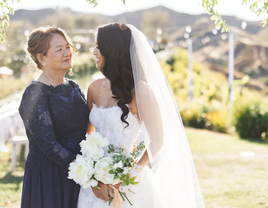 A bride and mother of the bride smile at each other