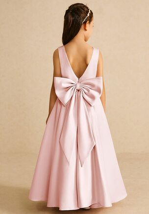 Pipsy is our classic matte satin flower girl dress. She features a scoop neckline, a V-back with a bow tie, and a pleated A-line skirt. This dress is not only perfect for a flower girl at a wedding but also versatile enough for other special occasions.