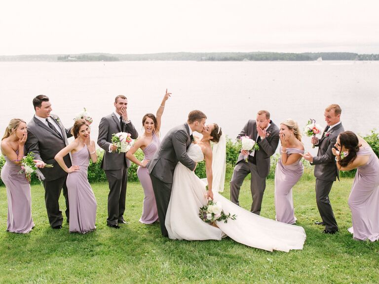Couple kissing surrounded by their wedding party celebrating