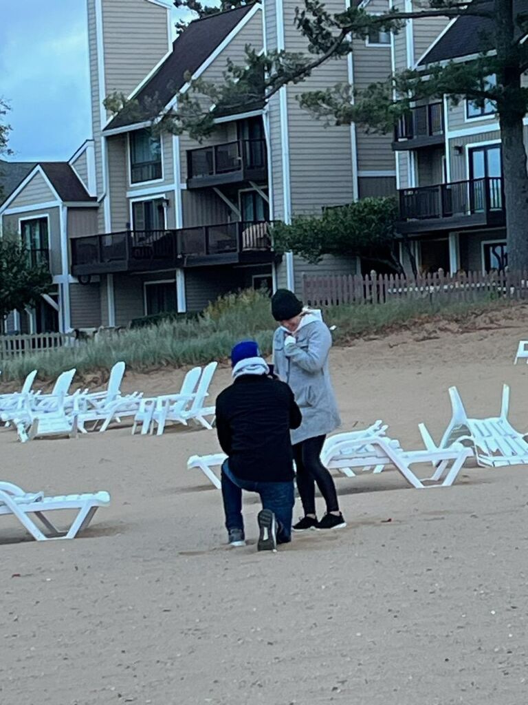 Our second trip to Traverse City, MI! 
 Adam proposed on the beach of our hotel, Grand Beach Resort Hotel.  There just so happened to be a random lady on the beach who decided to take our picture!  We were on our way back from exploring the Tunnel of Trees and I kept wanting to make stops on our way home (like a fudge/ice cream shop). Meanwhile, Adam had been waiting to get us back to the hotel before the sun set to propose!  Sorry I took so long, Adam!