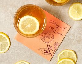 Orange napkin with floral illustration and names in purple calligraphy