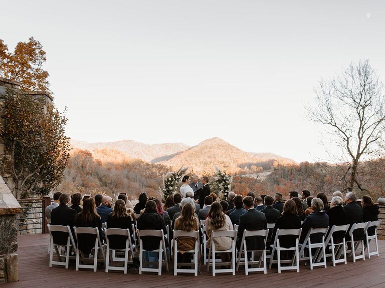 Happy couple exchanging their vows outside with a forest backdrop