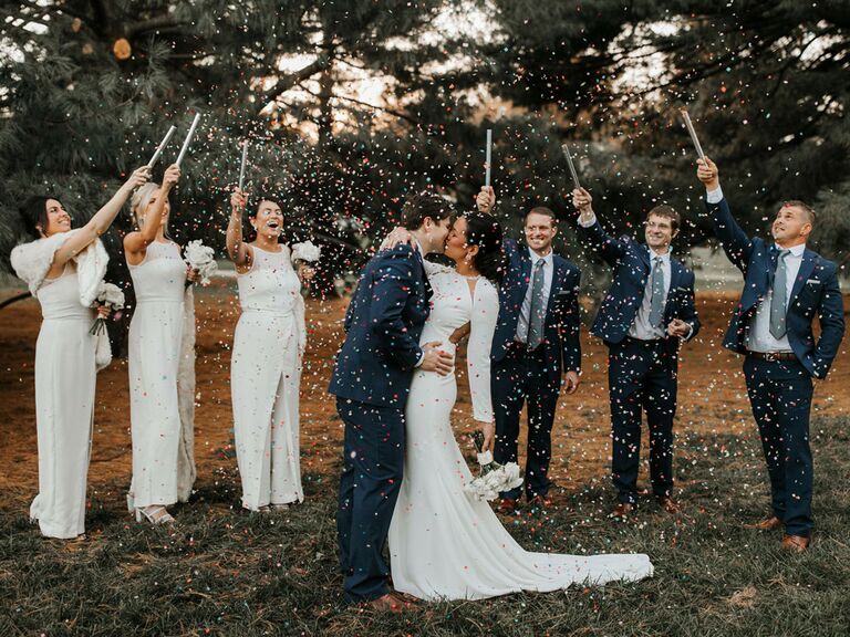 Bridesmaids and groomsmen tossing confetti over bride and groom