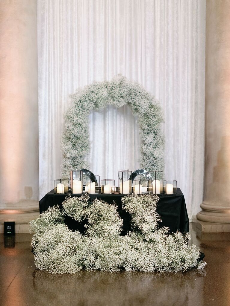 modern wedding sweetheart table idea decorated with white baby's breath arch, black tablecloth and white candles in black square vases