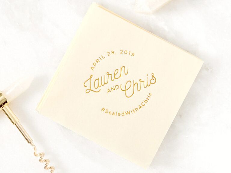 Cream napkin with names, date and wedding hashtag in curving in loopy gold script