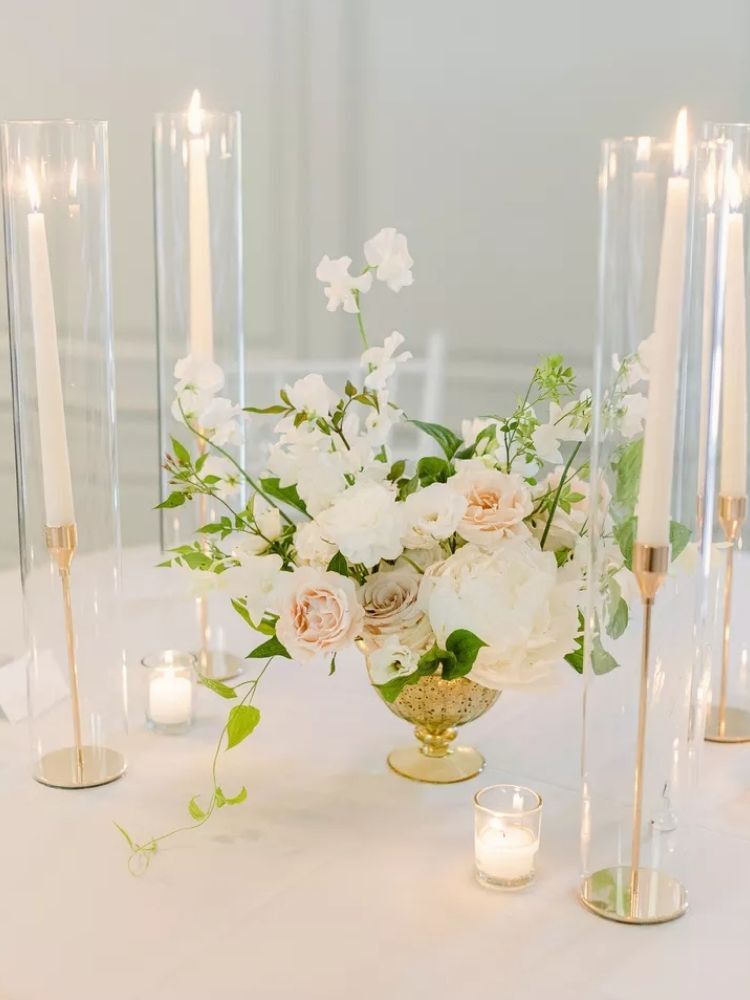 rose centerpiece in gold vase surrounded by taper candles