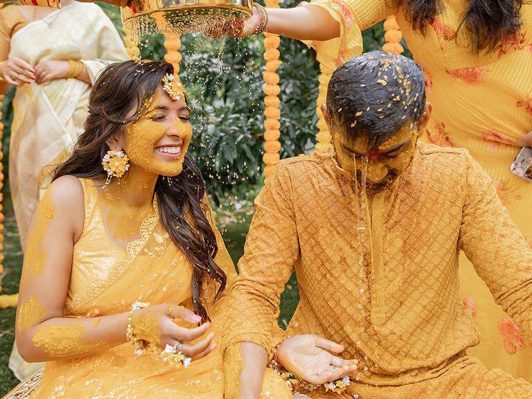 Indian couple covered in turmeric paste at haldi ceremony
