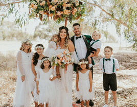 Bride and groom pose with kids at wedding.