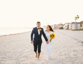 Bride and groom on a beach with a bouquet of sunflowers