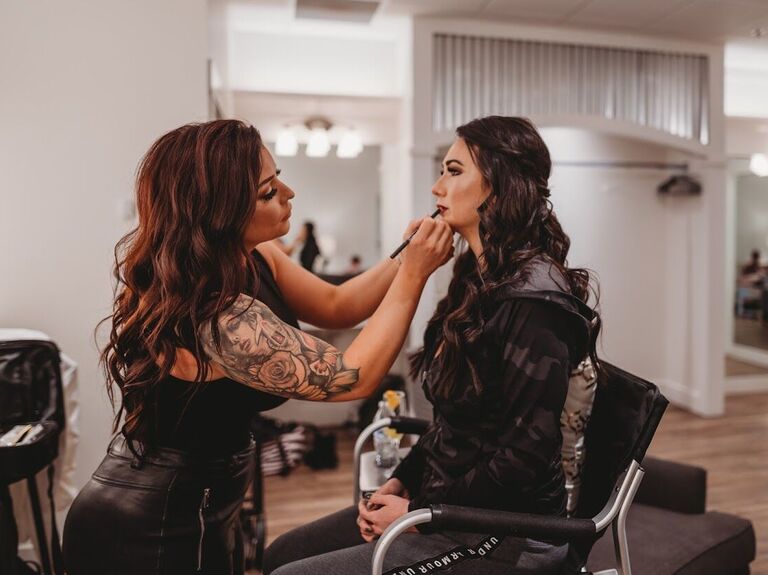 Makeup artist applying lipstick on her client to finish the look
