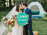 Couple kissing while holding camping-themed sign
