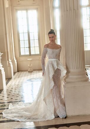 Chantilly lace and delicate lace overlays define the Lunaria gown from the Maison Blanche collection. The base dress opens with a dipped neckline, a fitted waist, and an abbreviated front hemline cascading to a floor-length finish. Exposed framing details trace the bodice before turning to a plunging open back. An expansive detachable overskirt sweeps into a combined chapel and court length train, while matching long sleeves attach or detach. Delicate belt detailing centers the waistline.