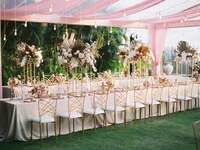 Boho wedding tent decorations with pampas grass centerpieces, colored drapes and Edison bulb lights