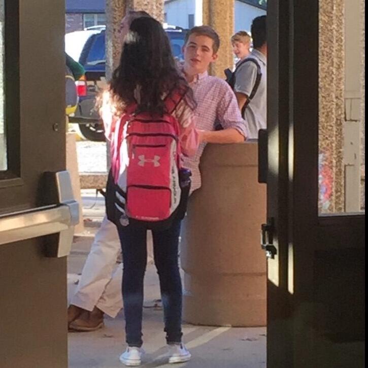 After what felt like eternity, Brendan finally asked Emily out after school while leaned up against a trash can (how romantic). Her friends watched from inside the building, snapped this shot, and then came out to celebrate with her once he left to drive a friend home.
