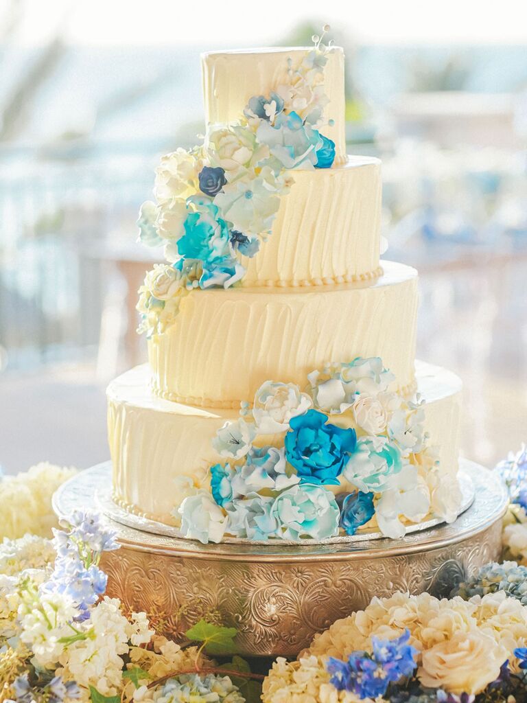 Four-tier beach wedding cake with watercolor blue cascading flowers