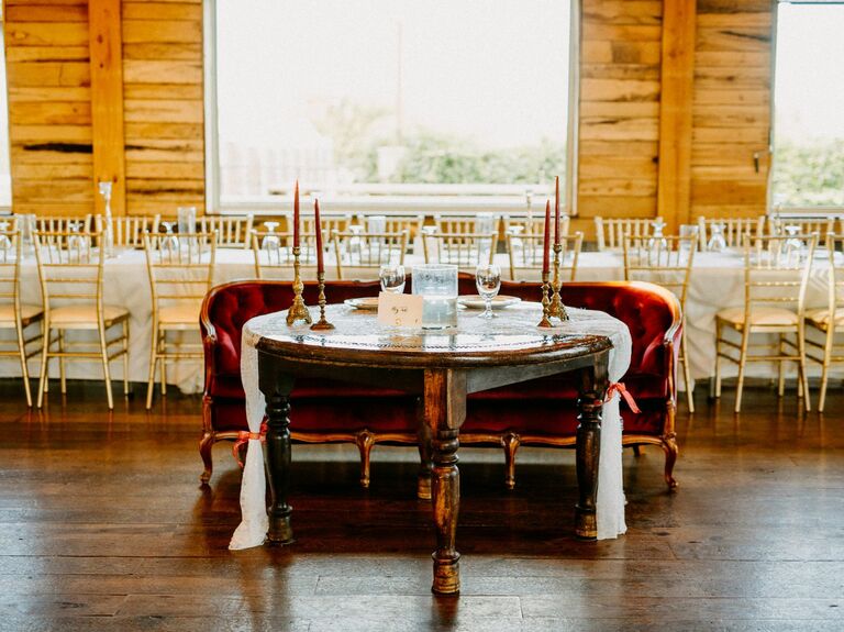 simple wedding sweetheart decor with red velvet antique loveseat, wooden table and brass candlesticks