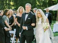 Father of the bride in black tuxedo walking his daughter down the aisle